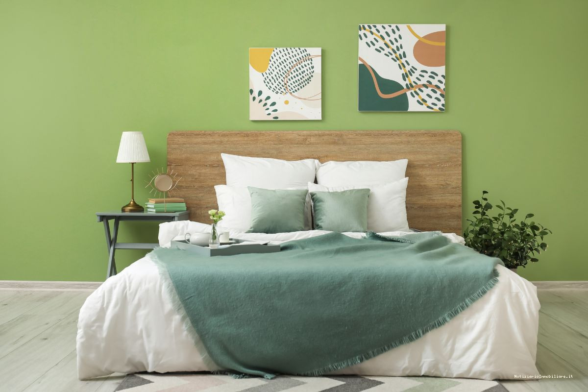 parete dietro letto matrimoniale verde con quadri a tema